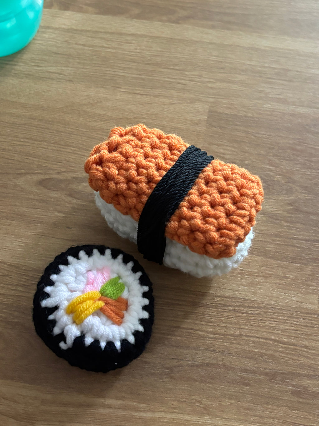 Two crocheted sushi toys on a wooden surface