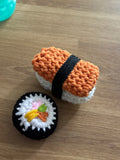 Two crocheted sushi toys on a wooden surface