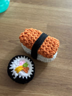 Two crocheted sushi toys on a wooden surface