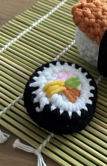 Crocheted sushi ornament on a bamboo mat