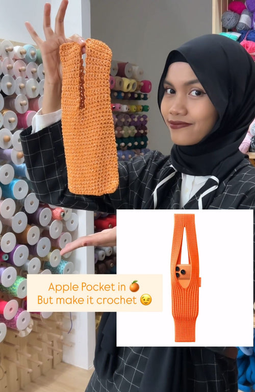 Person holding a crochet Apple Pocket with text overlay in a yarn store setting
