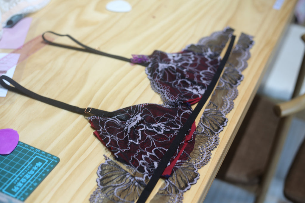A creator carefully sewing a lace bralette cup using a professional zigzag stitch for stretch and durability.